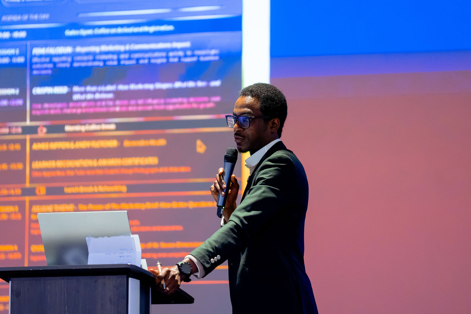A presenter discussing a programme framework on the main screen.